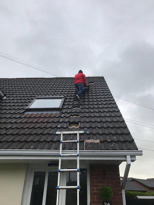 Man fixing roof tiles on a house