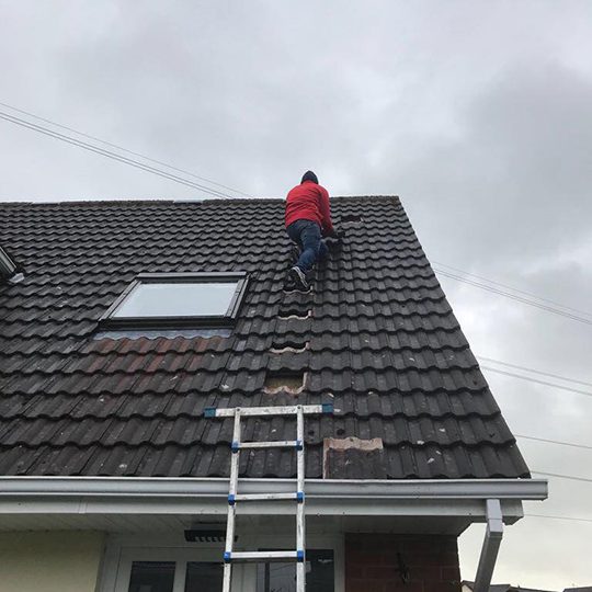 Man fixing roof tiles on a house